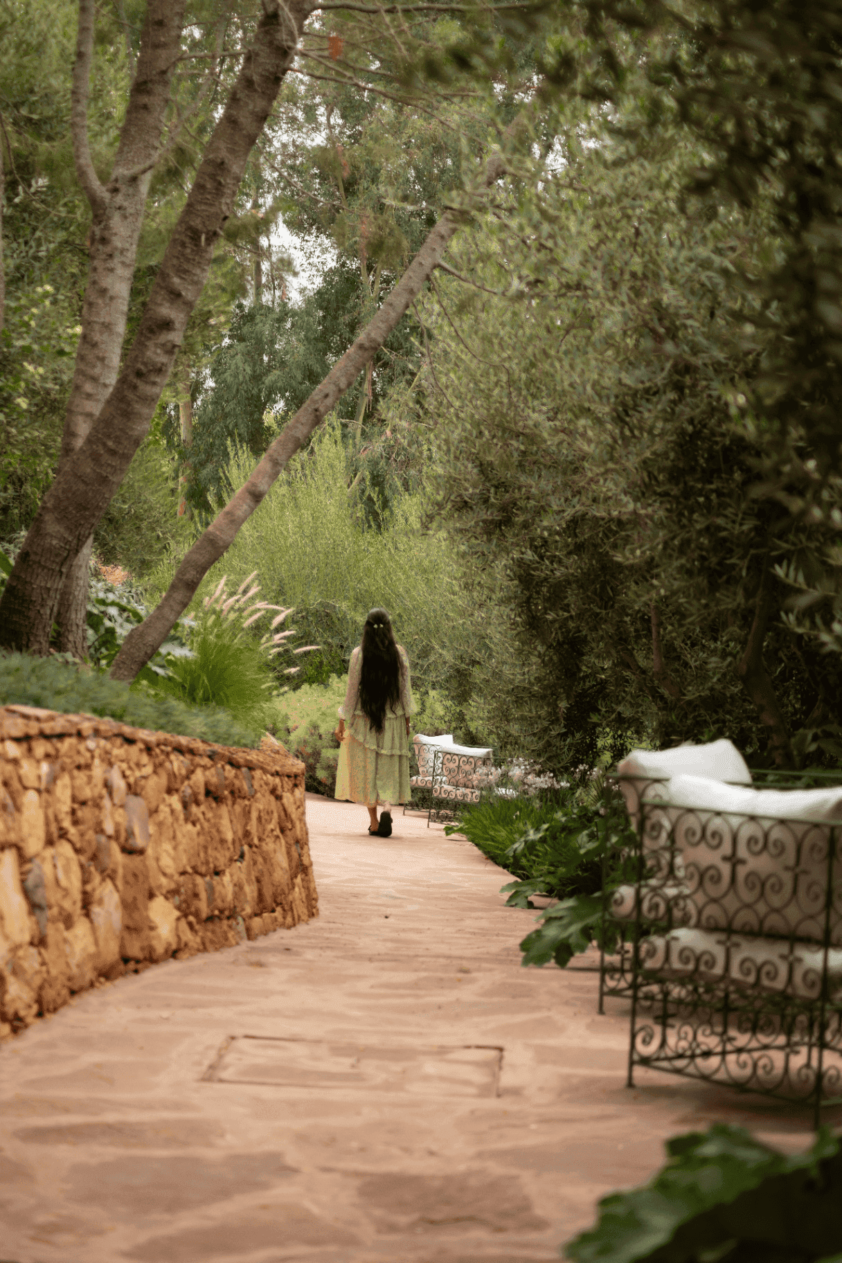 Serene garden pathway at PANGAEA Club with lush greenery and seating areas.